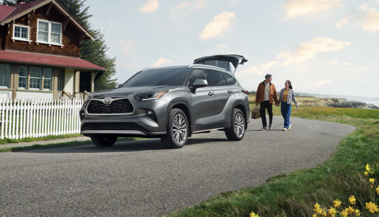 2025 toyota grand highlander parked infant of house with trunk open, couple walking towards car with a bag